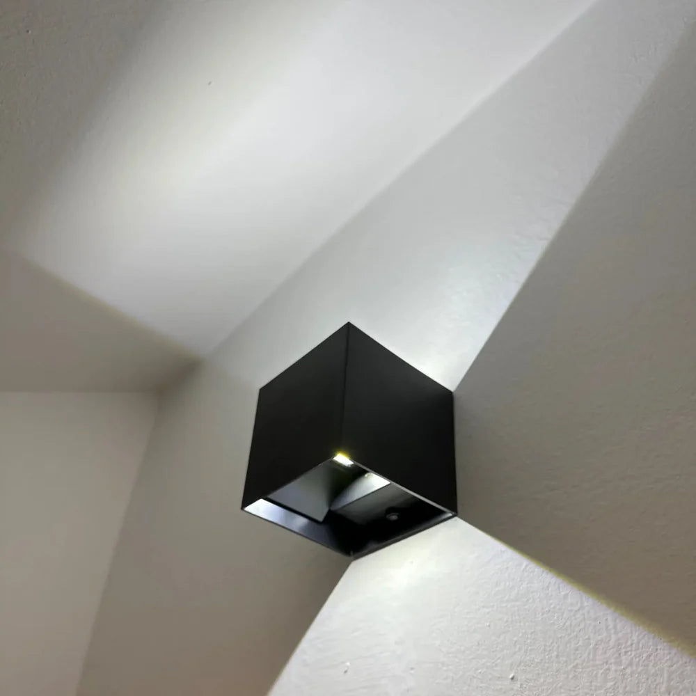SensoCube LED-Wandlampe in Schwarz an der Wand montiert mit Lichtkegel nach oben und unten