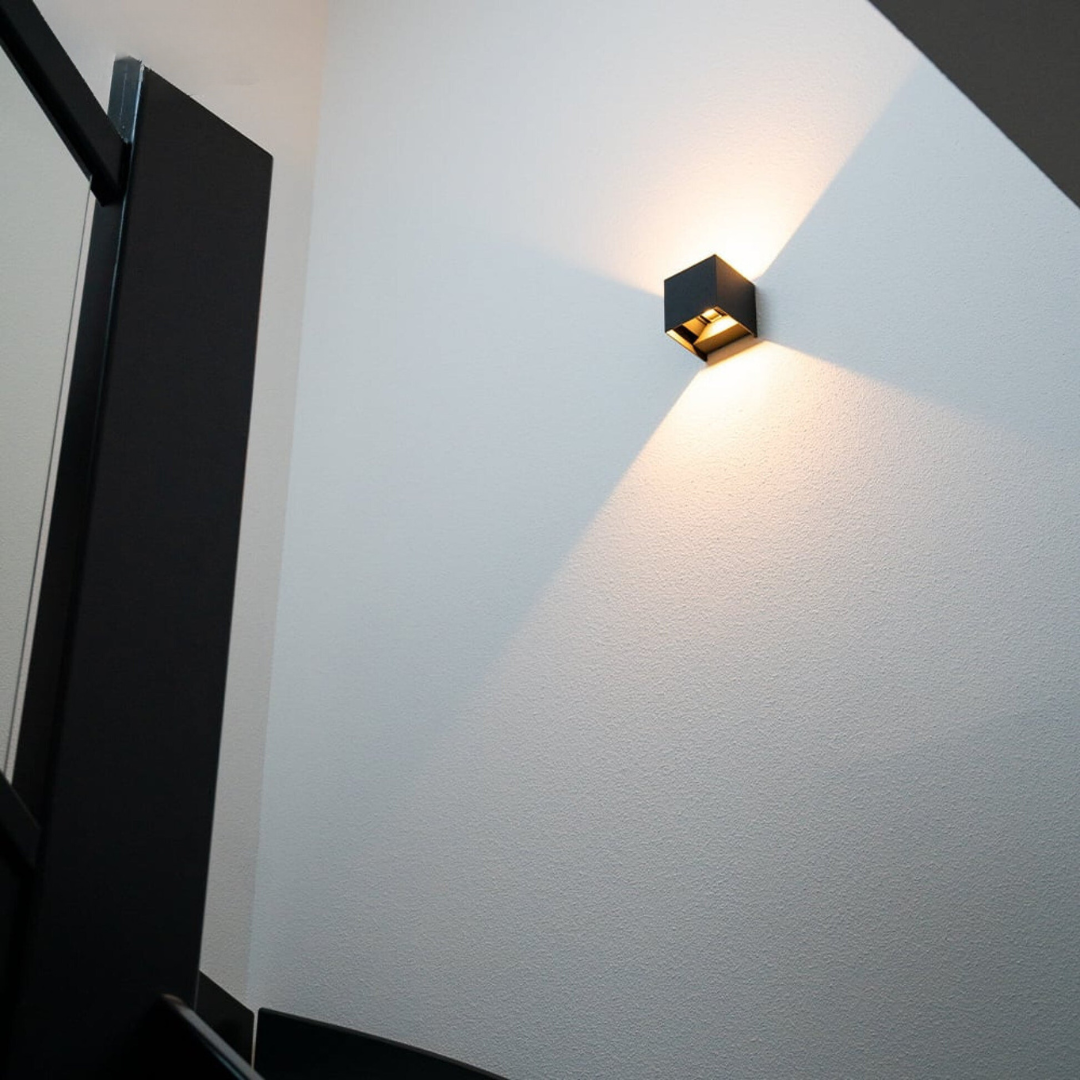 SensoCube Wandlampe in Schwarz an weißer Wand neben der Tür