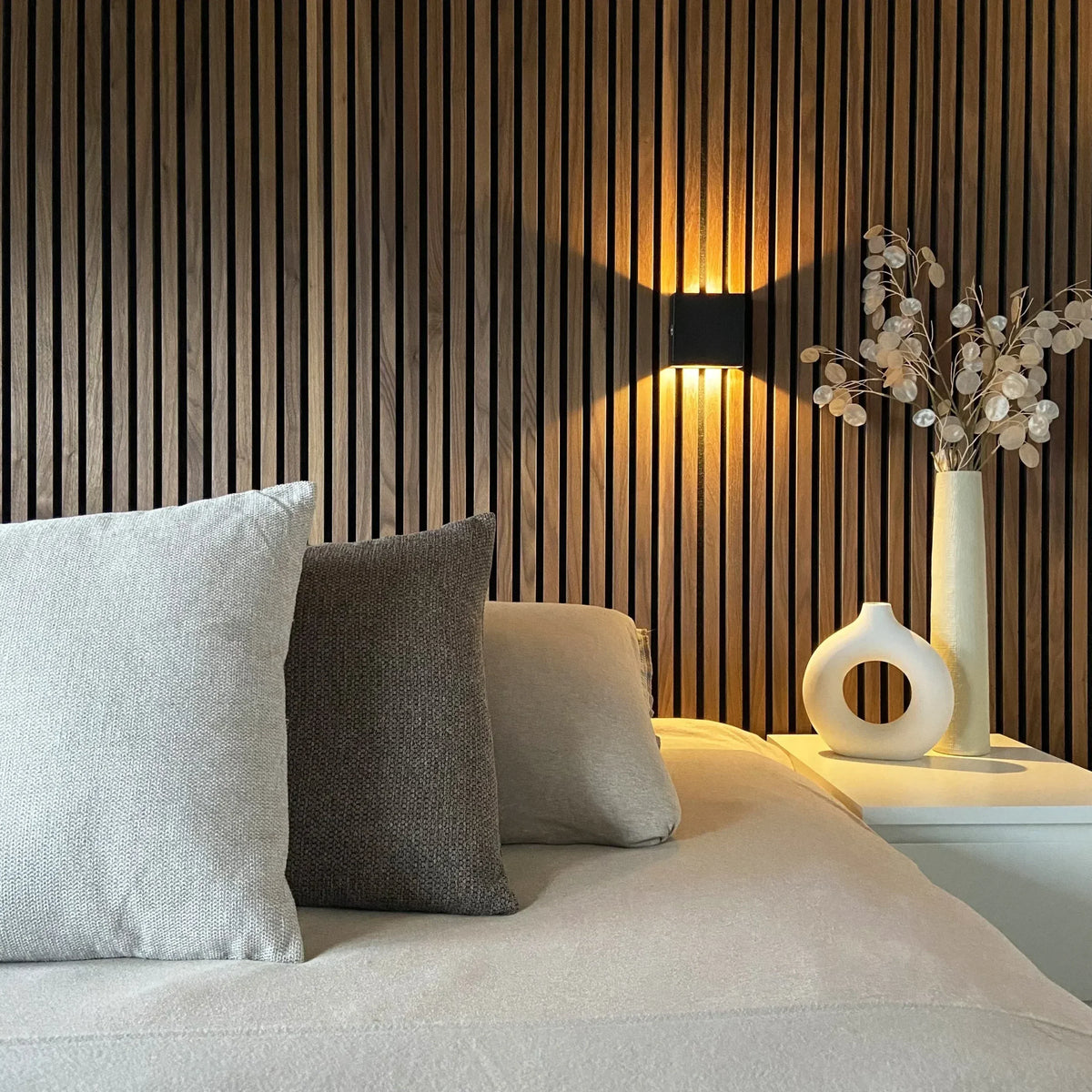 SensoCube Wandlampe in Schwarz über dem Bett an einer Holzlamellenwand